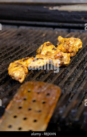 Glazed chicken wings on a restaurant grill with char marks. Stock Photo