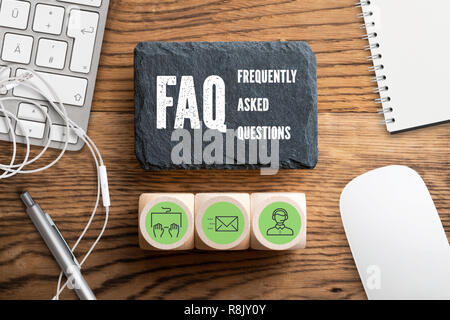 Slate plate with text "FAQ - frequently asked questions" on wooden background Stock Photo