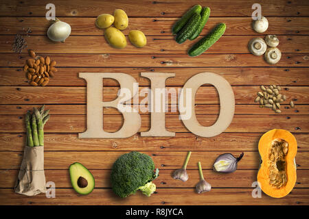 Word 'BIO' in wooden letters with many cooking ingredients on wooden background
