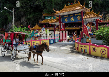 Ipoh, Malaysia - Apr 15, 2018: Unidentified visitors on horse coach passing by the entrance of Ling Sen Tong, Temple cave, Ipoh, Malaysia - Ling Sen T Stock Photo