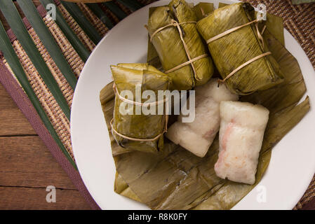 khao tom mad Thai food style dessert, made from banana and glutinous rice, wrap with banana leaf on wooden table Stock Photo