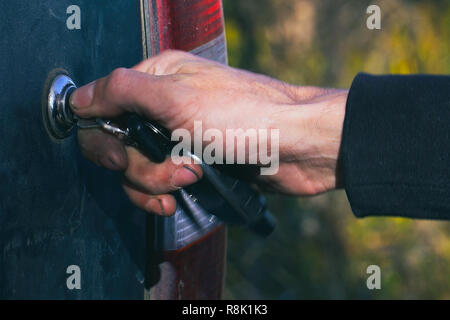 Man closes or opens the trunk of the car with a key Stock Photo