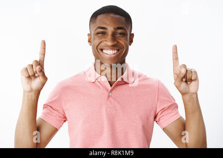 Portrait of charismatic good-looking pleasant and happy young african american guy lifting hands pointing up and smiling cheerfully with satisifed assertive expression, recommending cool copy space Stock Photo