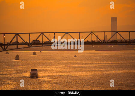 Traffic on bridge and boats and ferries  crossing  at Mactan Bridge Cebu in golden dusk and sunset at golden hour Stock Photo