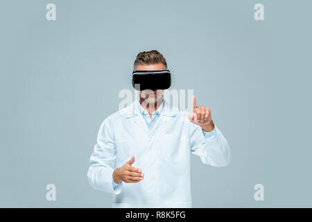 scientist in virtual reality headset moving something isolated on grey, artificial intelligence concept Stock Photo