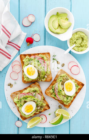 Toasts with avocado guacamole, fresh radish, boiled egg, chia and pumpkin seeds. Diet breakfast. Delicious and healthy plant-based food. Flat lay. Top Stock Photo