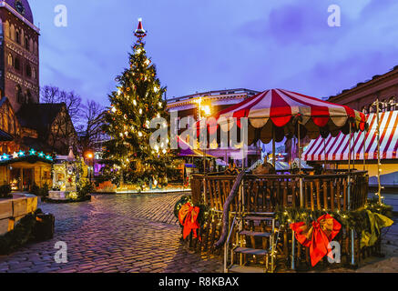 Carousel at Christmas market on Dome Square with Xmas tree and stalls in Riga in Latvia in winter. Eraly in the morning Stock Photo