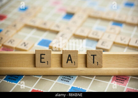 WOODBRIDGE, NEW JERSEY - November 9, 2018: Scrabble tiles spell out the word eat on a vintage game board Stock Photo