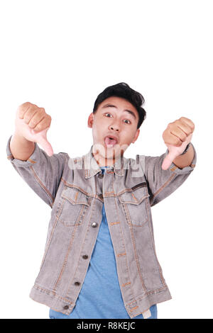 Photo image portrait of a cute young Asian man doing mocking gesture with tongue out and showing two thumbs down isolated on white Stock Photo