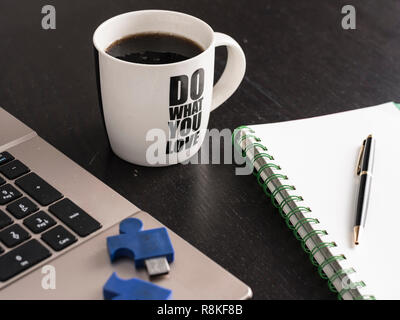 still life with blocknote, labtop, pen and a white mug of coffee over a black office desk. symbol of job Stock Photo