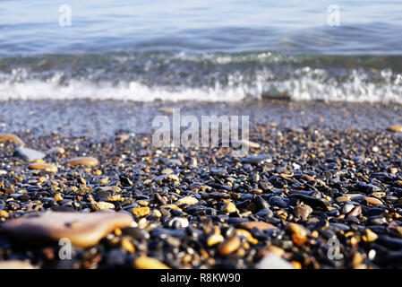 On the seashore there are many small stones of different shapes. sea surf and waves visible behind sea pebbles. Far East of Russia, Vladivostok Stock Photo