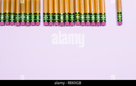 Many pencils in a row showing only the eraser end on white table with copy space. Stock Photo