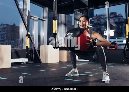 attractive asian girl exercising with medicine ball at gym