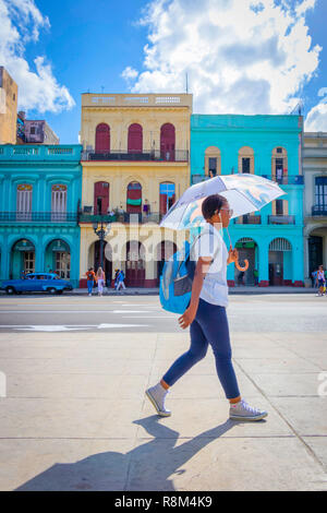 woman with umbrella walks past colourful buildings in Havana Cuba Stock Photo