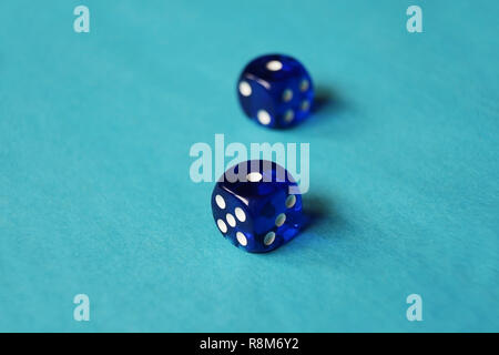 A vibrant monochromatic macro with depth of field about two blue glass gambling dice with two unlucky number one on blue background. Stock Photo