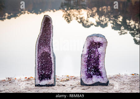 2 large amethyst crystals geodes near the water of a lake during sunset Stock Photo