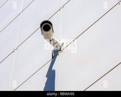 Surveillance camera mounted on a wall lined with ceramic tiles Stock Photo