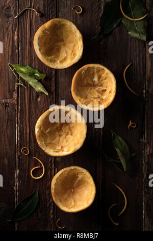 Four Squeezed Oranges Halves with Leaves on Wooden Surface Stock Photo