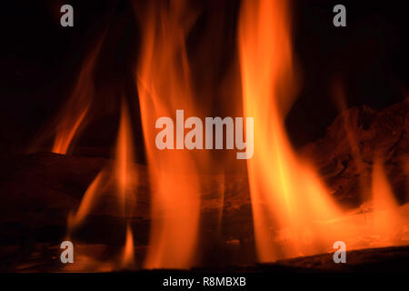 blazing flames of firewood in a fireplace, red glowing pieces of firewood in a indoor fireplace abstract macro shot Stock Photo