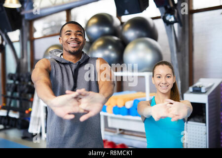 Young happy fitness girl with sporty body posing at studio on a blue  background. Beautiful fit Girl. Fitness model in white sports bodysuit  sitting on Stock Photo - Alamy