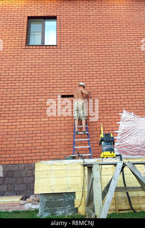 The builder performs work on the ladder 2018 Stock Photo