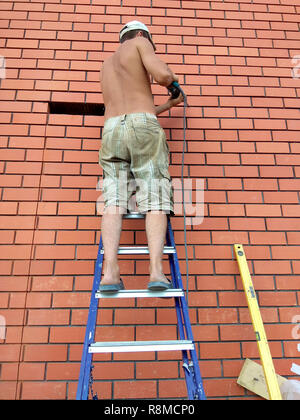 The builder performs work on the ladder 2018 Stock Photo