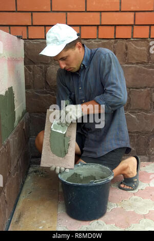 Professional worker gluing decorative tile on wall 2018 Stock Photo