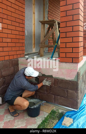 gluing a granite stone on the foundation of the building facing 2018 Stock Photo
