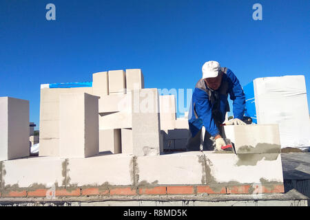 The master monitors the wall with gas blocks using glue and trowel 2018 Stock Photo