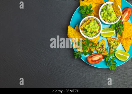 Guacamole and nachos with ingredients on the background of a black stone board. Top view, copy space. Stock Photo