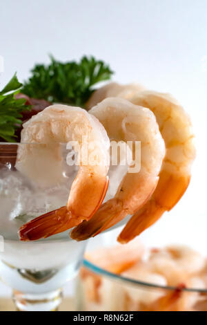 Close up side view of shrimp in a shrimp cocktail.  Shrimp and hung on the side of a margarita glass.  Blurred background. Stock Photo