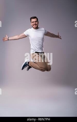 handsome man casual dressed celebrating and jumping on gray background Stock Photo