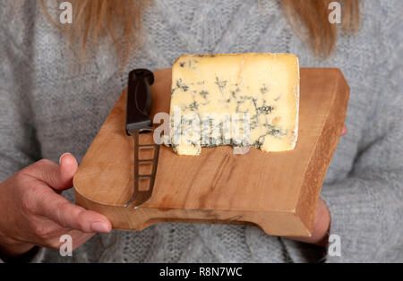Cheese board with a knife and piece of blue cheese. Stilton Cheese. Stock Photo