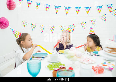 Jolly girls blowing party horns Stock Photo