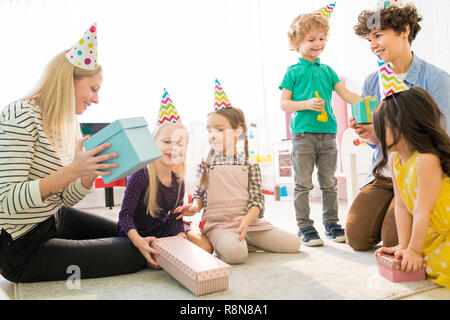 Mothers and children guessing what is inside of gift box Stock Photo