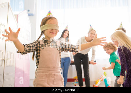 Positive blindfolded girl finding other players Stock Photo