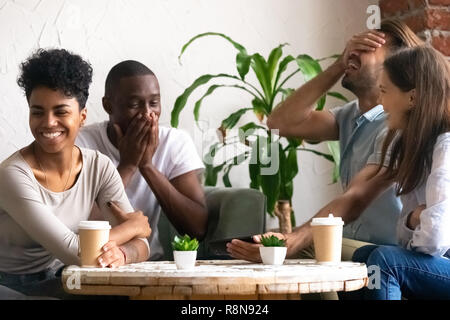Diverse excited friends having fun together in cafe Stock Photo
