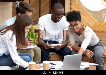 Smiling diverse friends doing paperwork together in cafe Stock Photo
