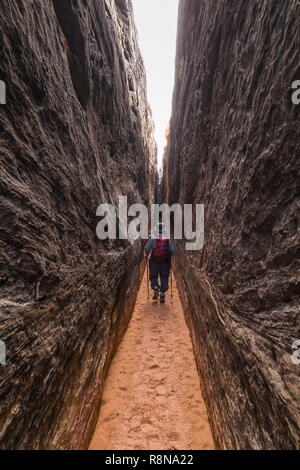 Karen Rentz squeezing through the Joint Trail along the Chesler Park Loop Trail in the Needles District of Canyonlands National Park, Utah, October, U Stock Photo