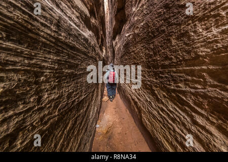 Karen Rentz squeezing through the Joint Trail along the Chesler Park Loop Trail in the Needles District of Canyonlands National Park, Utah, October, U Stock Photo