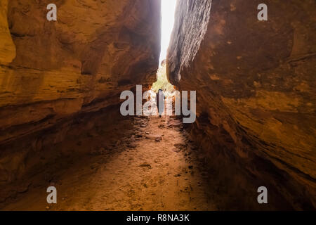 Karen Rentz squeezing through the Joint Trail along the Chesler Park Loop Trail in the Needles District of Canyonlands National Park, Utah, October, U Stock Photo