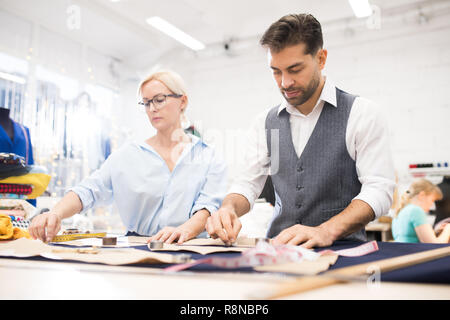 Tailors Working at Table in Atelier Studio Stock Photo