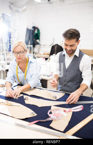 Tailors Working at Table in Atelier Stock Photo