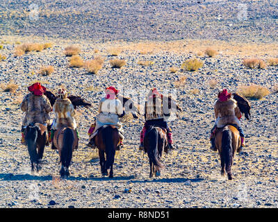 Mongolian Golden Eagle Hunter in traditional clothing riding on horseback to the Golden Eagle Hunter Festival competition site at Ugii in western Mong Stock Photo