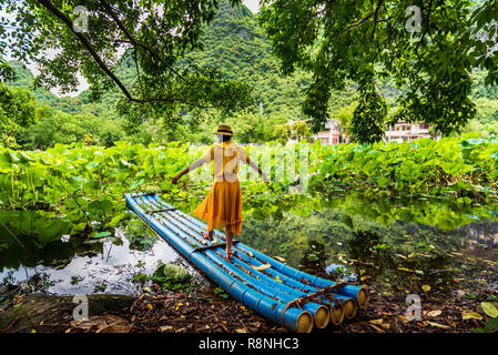 Girl standing on bamboo raft in lotus flower lake Stock Photo