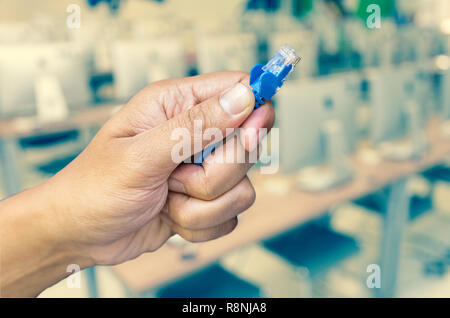 hand holding network cable on Abstract blurred photo of empty server room background, education and business concept Stock Photo