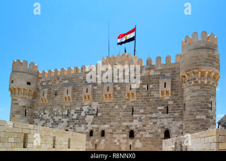 Egyptian national flag waving on a windy sunny day on top of Qaitbay citadel fortress - castle like architecture Stock Photo