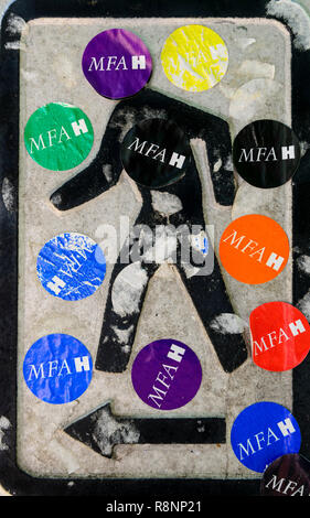 Traffic sign on pedestrian crossing with multiple MFAH stickers. Stock Photo