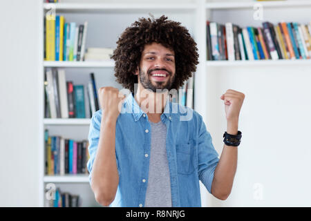 Cheering hipster man with afro hair indoor at home Stock Photo