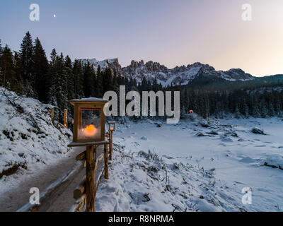 Romantic scene with candle lit path under moonlight towards tent village & dolomites above frozen lake Stock Photo